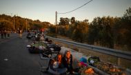 Migrants wake up as they spend the night on a road near Mytilene after a fire destroyed Greece's largest Moria refugee camp on the island of Lesbos, early on September 10, 2020.  AFP / ANGELOS TZORTZINIS
