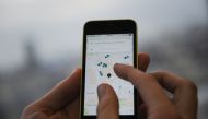 In this file photo taken on October 28, 2016 a man poses holding a smartphone showing the App for ride-sharing cab service Uber in London. Uber, September 28, wins appeal for new operating licence in London. / AFP / DANIEL SORABJI