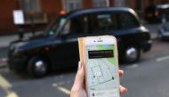 A woman poses holding a smartphone showing the App for ride-sharing cab service Uber in London.  AFP / Daniel LEAL-OLIVAS