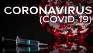 This photograph taken on October 7, 2020 shows a syringe on an illustration representing Covid-19 (novel coronavirus), in Toulouse, southwestern France. / AFP / Lionel BONAVENTURE
