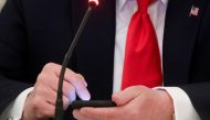 FILE PHOTO: U.S. President Donald Trump taps the screen on a mobile phone at the approximate time a tweet was released from his Twitter account, during a roundtable discussion on the reopening of small businesses in the State Dining Room at the White Hous