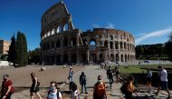 People wearing protective face masks walk past the Colosseum as local authorities in the Italian capital Rome ordered face coverings to be worn at all times outdoors, in an effort to counter the spread of the coronavirus disease (COVID-19), in Rome, Italy