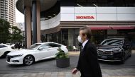A man walks past cars displayed outside a Honda showroom of company’s headquarters in Tokyo on November 6, 2020. / AFP / Philip FONG