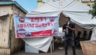 A man stands next to a sign at a blood donation station, calling for blood donation for the Ethiopian Defence Forces in the city of Gondar, Ethiopia, on November 06, 2020.  AFP / EDUARDO SOTERAS