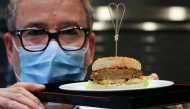 Chef Sam Brunschweiler wears a protective mask as he displays a pea protein-based hamburger with vegan juicy meat flavor, tomato, salad and sesame bun on a plate at flavour maker Givaudan's innovation centre in Kemptthal, Switzerland October 29, 2020. Reu