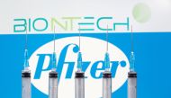 FILE PHOTO: Syringes are seen in front of displayed Biontech and Pfizer logos in this illustration taken November 10, 2020. REUTERS/Dado Ruvic/Illustration