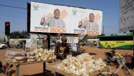A woman displays bread for sale near a campaign banner of presidential candidate Roch Kabore in Ouagadougou, Burkina Faso November 20, 2020. REUTERS/Zohra Bensemra
