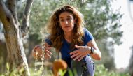 Elena Sampson, an owner of an olive grove and farm, sits by a an olive tree with a fungus growing nearby, as she gives an interview with AFP at her premises in the village of Akaki in central Cyprus on November 12, 2020. Standing in her olive grove in Cyp