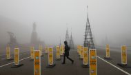 Pedestrians walk near near a skating rink past signs requesting to wear protective face masks and to keep a social distance amid the coronavirus disease (COVID 19) outbreak, as heavy fog covers a square named after Soviet state founder Vladimir Lenin in S