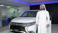 An official posing with the all-new Mitsubishi Outlander PHEV (Plug-In Hybrid Electric Vehicle) at Qatar Automobiles Company's (QAC) showroom in Qatar.