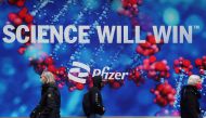 People walk past a Pfizer sign amid the coronavirus disease (COVID-19) pandemic in the Manhattan borough of New York City, New York, U.S., April 1, 2021. REUTERS/Carlo Allegri
