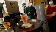 Chef Maria Munoz watches as a robot created by Spanish companies br5 and Mimcook makes paella during a demonstration at a warehouse in San Fernando de Henares, outside Madrid, Spain, May 20, 2021. Picture taken May 20, 2021. (REUTERS/Susana Vera)