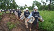 Handlers carry mine detection rats in their transport cages to work in an area being demined in Preah Vihear province, Cambodia, June 11, 2021. Picture taken June 11, 2021. REUTERS/Cindy Liu