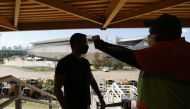 Soccer Football - Copa America 2021 - A worker at the stadium checks the temperature of another worker, before they are allowed to enter REUTERS/Mariana Greif 