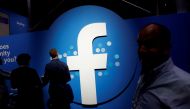 Attendees walk past a Facebook logo during Facebook Inc's F8 developers conference in San Jose, California, U.S., April 30, 2019. Reuters/Stephen Lam/File Photo
