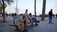 :FILE PHOTO: People wearing protective face masks sit on a bench in front of the Barceloneta beach, amid the coronavirus disease (COVID-19) outbreak, in Barcelona, Spain April 2, 2021. REUTERS/Nacho Doce/File Photo
