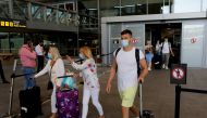 FILE PHOTO: Tourists wearing protective face masks walk with their luggage as they arrive at Malaga-Costa del Sol Airport, in Malaga, Spain, June 7, 2021. REUTERS/Jon Nazca//File Photo

