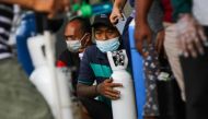 Men wearing protective face masks wait outside a store with their oxygen cylinders to get them refilled, amid a surge of coronavirus disease (COVID-19) cases, in Surabaya, East Java Province, Indonesia July 12, 2021, in this photo taken by Antara Foto. Di