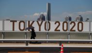 July 19, 2021 A woman shelters from the sun under an umbrella as she walks past Olympics signage REUTERS/Thomas Peter