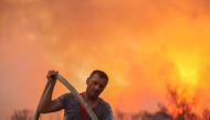 A volunteer firefighter holds a hose during a wildfire at Varympompi suburb north of Athens, Greece, August 3, 2021. REUTERS/Giorgos Moutafis