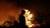 A man is silhouetted as he watches a wildfire burning in the village of Lasdikas near ancient Olympia, Greece, August 5, 2021. Picture taken August 5, 2021. REUTERS/Giorgos Moutafis
