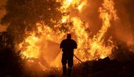 A firefighter tries to extinguish a wildfire burning in the village of Pefki, on the island of Evia, Greece, August 8, 2021. REUTERS/Nikolas Economou