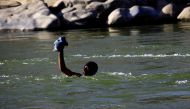 FILE PHOTO: An Ethiopian fleeing fighting in Tigray region lifts his clothes as he crosses the Setit river on the Sudan-Ethiopia border in Hamdayet village in eastern Kassala state, Sudan November 22, 2020. REUTERS/Mohamed Nureldin Abdallah