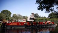 Pianist Masayuki Tayama steers his canal boat concert hall, named The Piano Boat, along the Colne Valley Canal in Harefield, Britain, September 8, 2021. Picture taken September 8, 2021. REUTERS/Henry Nicholls
 