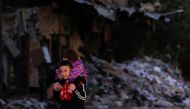 FILE PHOTO: A boy carries a child past damaged buildings at the Yarmouk Palestinian refugee camp on the southern outskirts of Damascus, Syria December 1, 2020. REUTERS/Omar Sanadiki/File Photo