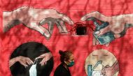 A woman walks past a graffiti, on a street, amidst the spread of the coronavirus disease (COVID-19) in Mumbai, India, April 6, 2021. REUTERS/Francis Mascarenhas/File Photo
