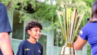 A young football fan posing for a photograph with the CONCACAF Champions' Trophy.