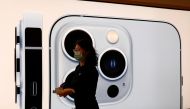 An Apple employee wearing a face mask walks past an image of an iPhone 13 Pro at an Apple Store on the day the new Apple iPhone 13 series goes on sale, in Beijing, China, September 24, 2021. REUTERS/Carlos Garcia Rawlins/File Photo