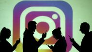 FILE PHOTO: Silhouettes of mobile users are seen next to a screen projection of Instagram logo in this picture illustration taken March 28, 2018. REUTERS/Dado Ruvic/Illustration