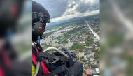 Powered paraglider delivers supplies to residents affected by flood in Sukhothai province, Thailand September 26, 2021 in this picture obtained from social media on September 28, 2021. The Charity Of Phitsanulok Association/via REUTERS