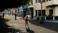 A woman walks with an umbrella to protect herself from the falling ash following the eruption of a volcano on the Canary Island of La Palma, in Los Llanos de Aridane, Spain, October 1, 2021. REUTERS/Borja Suarez