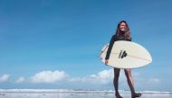 A surfing business owner, 38-year-old, Halfia Lando poses holding a surfboard at a Kuta beach as Indonesia opens up the tourist island of Bali to some countries. Reuters/Sultan Anshori 