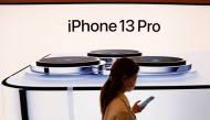 A woman wearing a face mask walks past an image of an iPhone 13 Pro at an Apple Store in Beijing, China, September 24, 2021. REUTERS/Carlos Garcia Rawlins/File Photo
