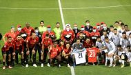 Al Rayyan and Al Wakrah players and officials pose for a photograph displaying jerseys with Ousmane Coulibaly's name on them.   