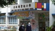 People wearing face masks walk outside a primary school, following coronavirus disease (COVID-19) infections in Hong Kong, China January 11, 2022. REUTERS/Lam Yik