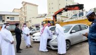 Officials inspect and mark an abandoned car in Doha, yesterday. 