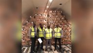 Qatar Airways Cargo employees pose with boxes full of roses behind them.
