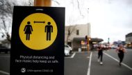 FPeople jog past a social distancing sign on the first day of New Zealand's new coronavirus disease (COVID-19) safety measure that mandates wearing of a mask on public transport, in Auckland, New Zealand, August 31, 2020. REUTERS/Fiona Goodall/File Photo

