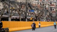 A man climbing a tree looks over barriers, which have been built to separate buildings from a street, amid the coronavirus disease (COVID-19) pandemic in Shanghai, China March 22, 2022. REUTERS/Aly Song