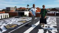 Russian artist Pokras Lampas and Ukrainian Alex Shtefan pose with one of nine of Pokras' calligraphy artwork on the rooftop of Alex's villas in Bali, Indonesia on March 16, 2022. REUTERS/Sultan Anshori
