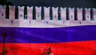 A woman rides a bicycle past a part of the Kremlin wall where the Russian national flag is projected, during celebrations of Russia Day in Moscow, Russia, June 12, 2020. REUTERS/Maxim Shemetov/File Photo

