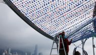 People wearing face masks work next to Victoria Harbour, amid the coronavirus disease (COVID-19) pandemic, in Hong Kong, China, March 25, 2022. REUTERS/Tyrone Siu