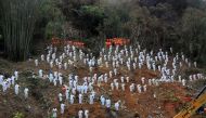 Rescue workers stand in a silent tribute at the site to mourn the victims of a China Eastern Airlines Boeing 737-800 plane, flight MU5735, that crashed in Wuzhou, Guangxi Zhuang Autonomous Region, China, March 27, 2022. Picture taken March 27, 2022. cnsphoto via REUTERS
