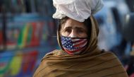 A woman wears a mask to prevent contracting the coronavirus disease (COVID-19) as she carries a bag of supplies on her head in Karachi, Pakistan, January 26, 2022. REUTERS/Akhtar Soomro