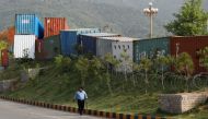 A police officer walks along shipping containers which are used to block the area leading towards the Red Zone and parliament building, in Islamabad, Pakistan April 3, 2022. Reuters/Akhtar Soomro