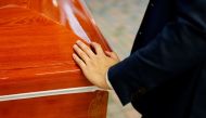Hades Chan, funeral director of YuXiang Funeral Company, places his hand over a coffin of coronavirus disease (COVID-19) victim before cremation, in Hong Kong, China, April 1, 2022. Reuters/Tyrone Siu